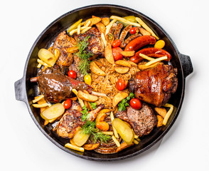 Meat assortment on a large frying pan, potato slices and braised cabbage. On a white background