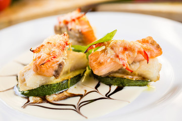 Fried zucchini with slices of salmon. On a white plate