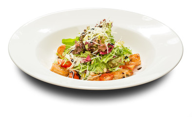 Salad with shrimp and arugula decorated with pine orehami.Na white plate and a white background