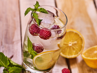 On wooden boards glass with raspberry alcohol cocktail and ice cubes. Cocktail number three hundred thirty nine cocktail raspberry mojito with lime and mint leaf.
