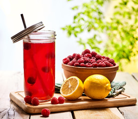 Wooden boards is ice cold drink glass with raspberry lemon cocktail . Country ice cold cocktail three hundred fourty two with raspberry clay bowl outdoor .