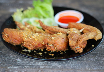 Fried chicken in black dish with sauce and vegetable.