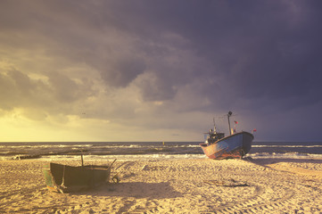 Łodzie na plaży podczas sztormu,kolorystyka retro - obrazy, fototapety, plakaty