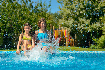 Kids in swimming pool have fun and splash in water, children on family vacation
