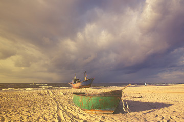 Łodzie na plaży podczas sztormu,kolorystyka retro - obrazy, fototapety, plakaty