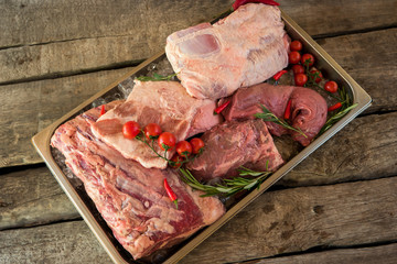 Tray with meat and ice. Tomatoes and rosemary. Pork and beef. Source of amino acids.