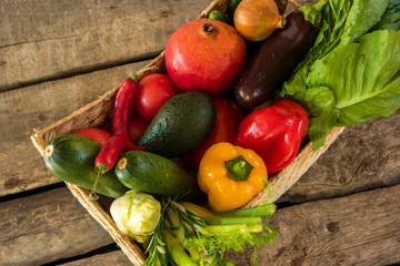Chili peppers and pomegranate. Basket with wet vegetables. Different ingredients for salad. Food on old brown table.