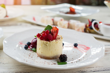 Plate with small cake. Dessert with mint and raspberry. Chocolate crumbs on cheesecake. Recipe of healthy dessert.