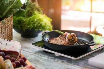 Cooked meat of brown color. Garlic on frying pan. Hot beef steak. Breakfast prepared in restaurant.