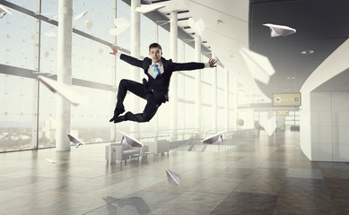 Jumping businessman in office . Mixed media