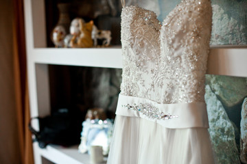 Wedding dress embroidered with crystals and pearls hangs on the