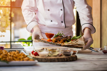 Cooked meat with herbs. Chef holds dish. Juicy grilled pork with vegetables. Delicacy from restaurant menu.