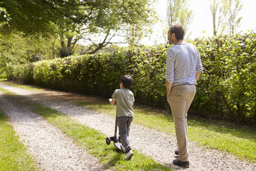 Fototapeta premium Rear View Of Father And Son Walking In Summer Countryside