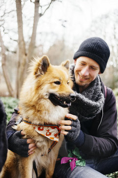 Smiling man looking at Eurasier in park
