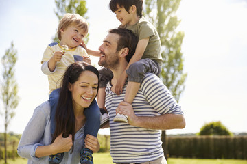 Parents Giving Sons Ride On Shoulders During Walk