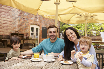 Family Sitting At Outdoor Cafe Table Having Lunch