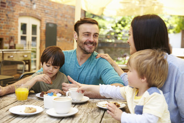 Family Sitting At Outdoor Cafe Table Having Lunch