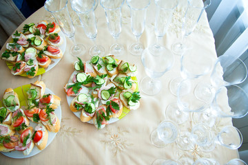 Canapes with cucumbers and greenery served on white plates