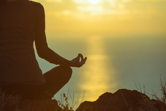 Woman Meditating And Relaxing Her Mind In A Beautiful Sunset Setting. 