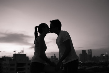 Young couple in the city kissing on a roof top. 