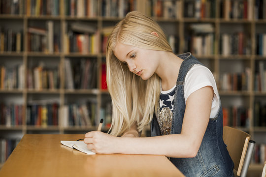 Teenage girl studying at desk in library