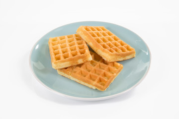 Drei eckige Waffeln liegen auf einem blauen Teller. Hintergrund weiss.