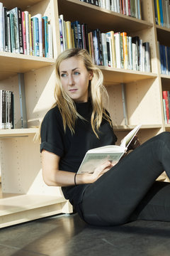 Female student looking away while sitting in college library