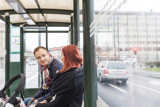Couple conversing while waiting at bus stop