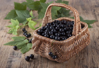 Fototapeta na wymiar Black currants in a basket on the old wooden table