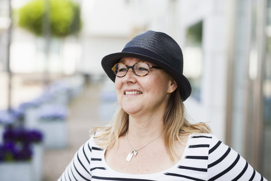 Happy mature woman wearing glasses and hat outdoors