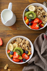 Two bowls with fruits granola and jug of milk