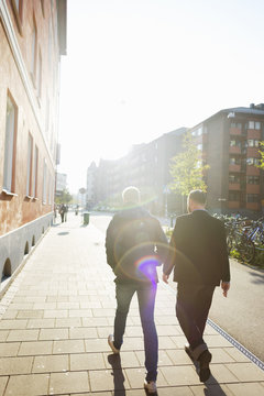 Full length rear view of businessmen walking on sidewalk