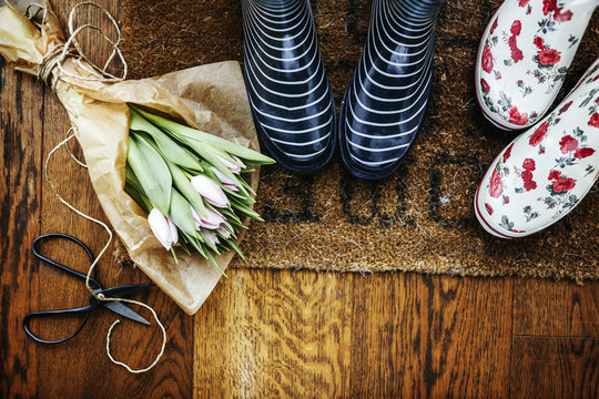 High angle view of gardening boots by tulip bouquet and scissors on hardwood floor