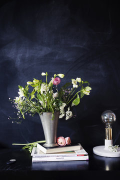 Electric lamp with books and flower vase on table in class