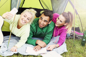 Group of friends camping in forest and taking selfie