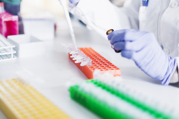 Researchers hand mixing solution from pipette in test tube at lab