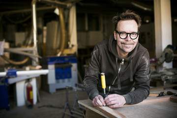 Portrait of smiling carpenter with chisel in workshop