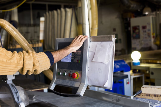 Carpenter's hand using monitor on table saw machine in workshop