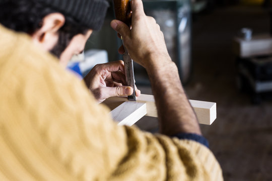 Carpenter using chisel on wood in workshop