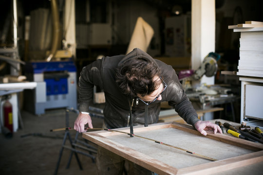 Carpenter holding folding ruler while making frame in workshop