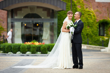 Naklejka premium Smiling bride leans to a groom standing in the front of hotel en