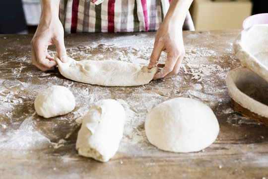 Baker's hands kneading dough at table in bakery