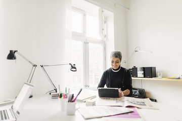 Businesswoman using digital tablet at desk in office