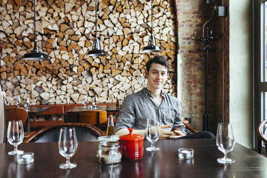 Portrait of smiling man sitting at table in restaurant