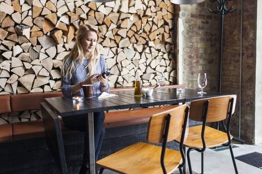 Woman sitting at restaurant table and looking at smartphone