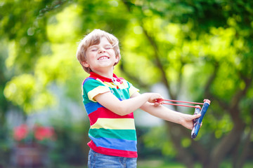 little kid boy shooting wooden slingshot