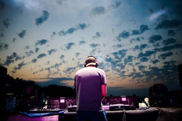 Club, disco DJ playing and mixing music for crowd of happy people. Nightlife, concert lights, flares