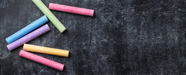 Pieces of school chalk on old black chalkboard