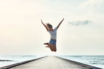Foto op Plexiglas Happy jumping girl on the pier © GVS