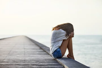 Foto op Plexiglas Sad lonely beautiful woman sitting on the pier © GVS